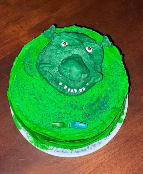 Gâteau rond vert représentant un visage de type "Shrek" avec une expression effrayante.