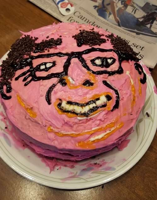 Gâteau avec un visage humain mal fait, yeux disproportionnés et dents noires.