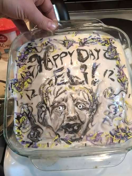 Gâteau avec visage effrayé et inscription d'anniversaire, parsemé de vermicelles.