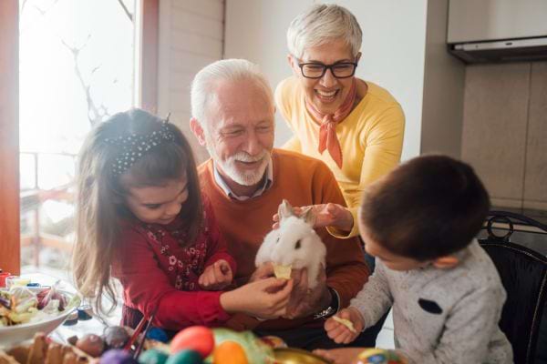 Famille avec grands-parents montrant un lapin aux enfants pendant Pâques.