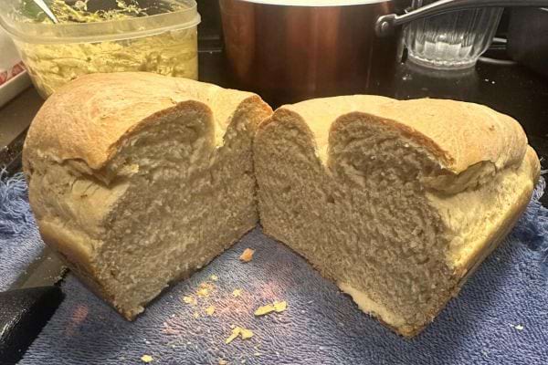 Gros pain tranché en deux, montrant une mie dense et uniforme, sur un torchon bleu.