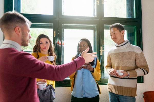 Quatre amis discutant vivement autour de tasses de café dans un intérieur lumineux.