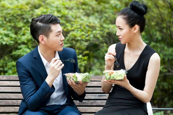Deux personnes âgées asiatiques pratiquent le tai chi dans un parc.