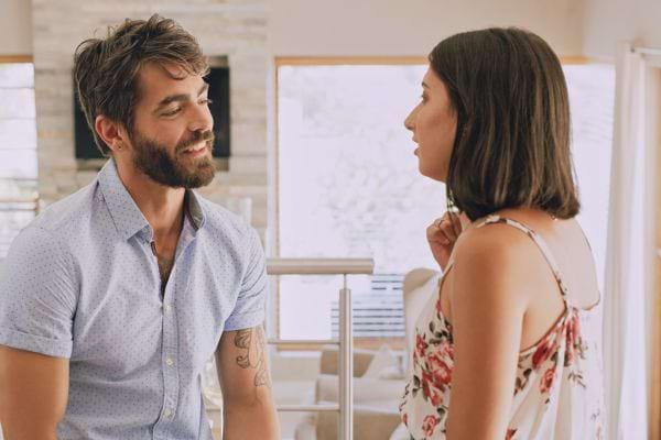 Un couple dans une discussion animée dans un intérieur lumineux.