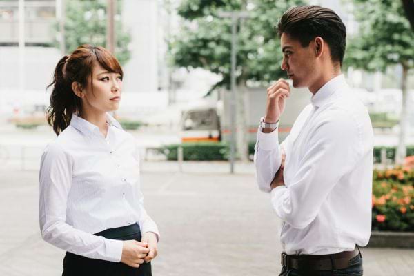 Un homme et une femme en tenue de travail engagés dans une conversation sérieuse à l'extérieur d'un bureau.