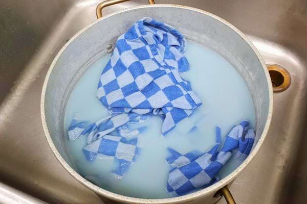 Vêtements bleus et blancs trempant dans une bassine d'eau bleue.