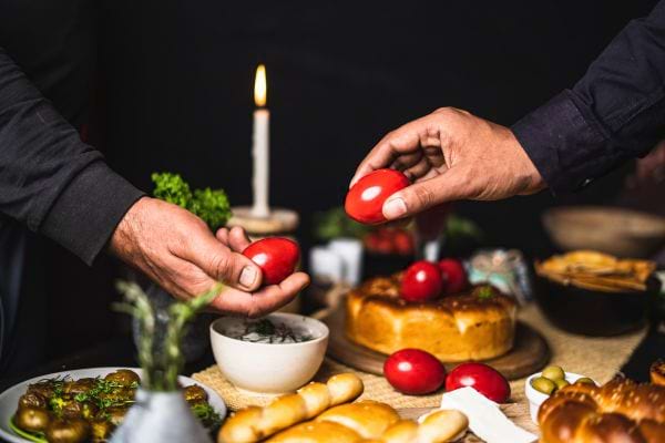 Deux hommes échangeant des œufs de Pâques rouges lors d'un repas festif.
