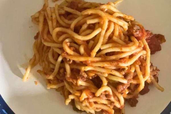 Spaghetti à la sauce bolognaise sur une assiette beige.