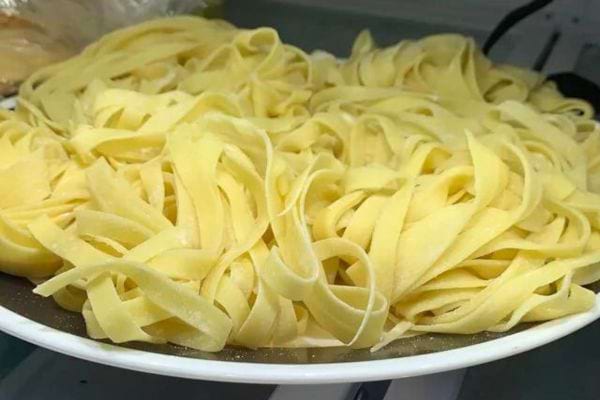 Tagliatelles jaunes fraîches non cuites empilées sur une assiette.