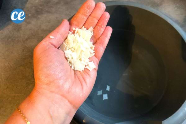 Main tenant des copeaux de savon de Marseille, ingrédient pour recette de dégraissant maison.