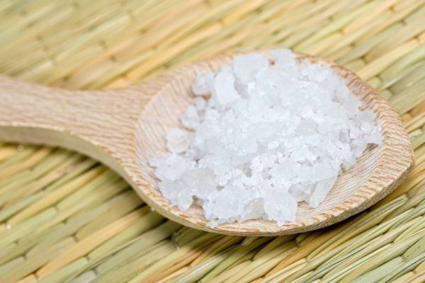 Gros sel sur une cuillère en bois placée sur un tapis de bambou, utilisé pour des rituels de purification.