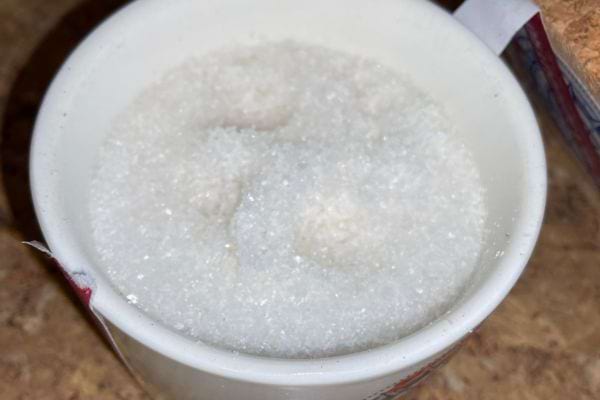 Tasse blanche remplie de gros sel blanc.