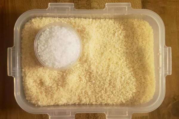 Gros sel dans un conteneur en plastique avec un petit bol de sel au centre.