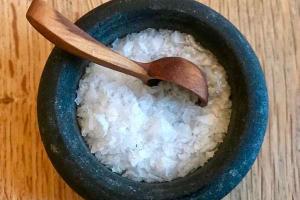 Gros sel dans un mortier noir avec une petite cuillère en bois