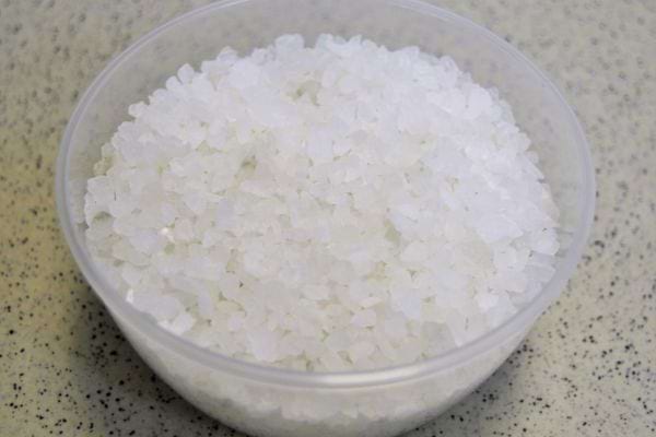 Bol en plastique rempli de gros sel sur un comptoir de cuisine, prêt pour l'usage domestique protecteur.