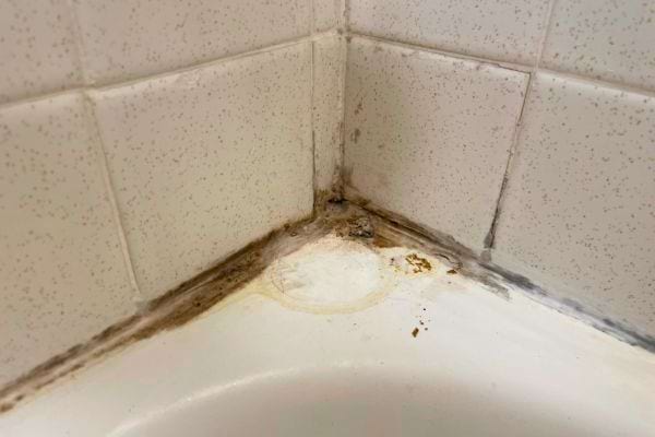 Coin de baignoire avec joint de silicone jauni et dégradé, nécessitant remplacement.