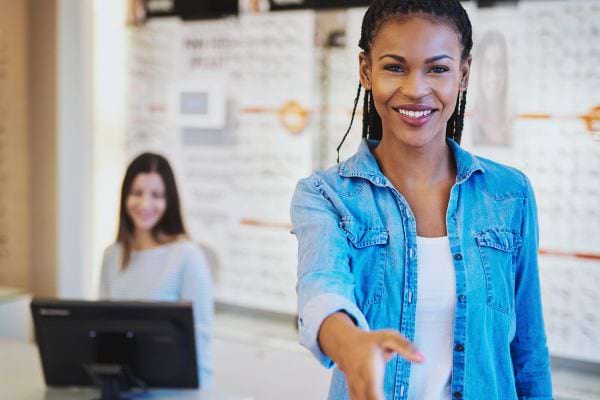 Employée souriante tend la main dans un espace de vente.