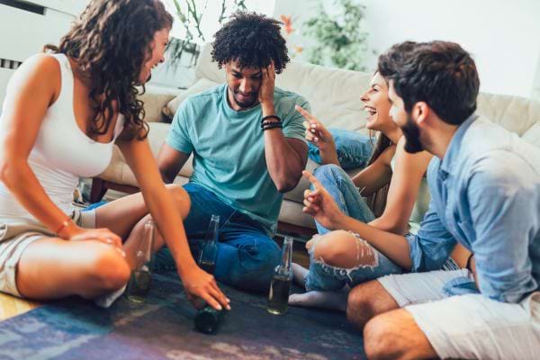 Quatre amis jouant et discutant dans un salon.
