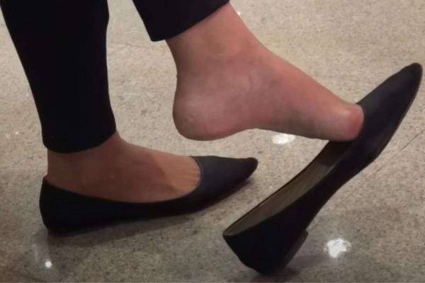 Pied retirant un escarpin noir.