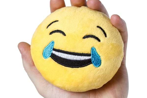 Peluche emoji riant aux larmes tenue dans une main.