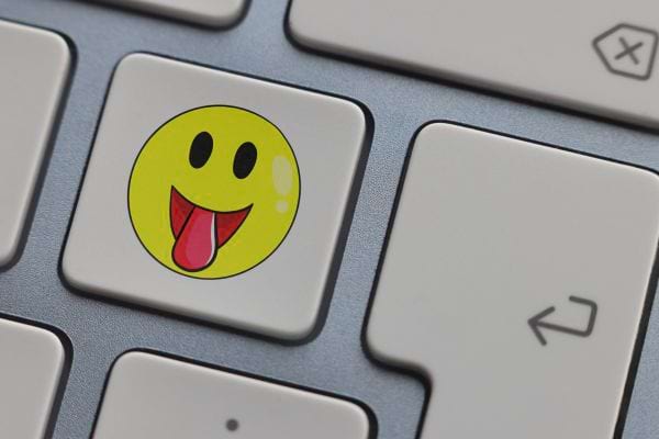 Emoji souriant avec langue sur touche de clavier.