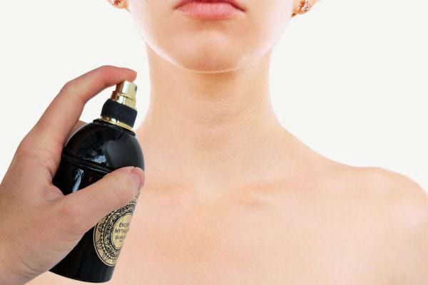 Femme appliquant du parfum sur son cou.