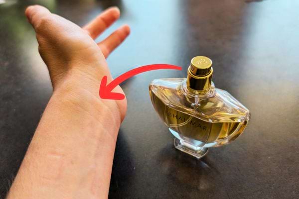Main montrant un flacon de parfum, flèche vers le poignet.