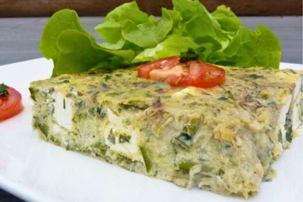 Flan aux courgettes et fromage, servi avec une garniture de tomate.