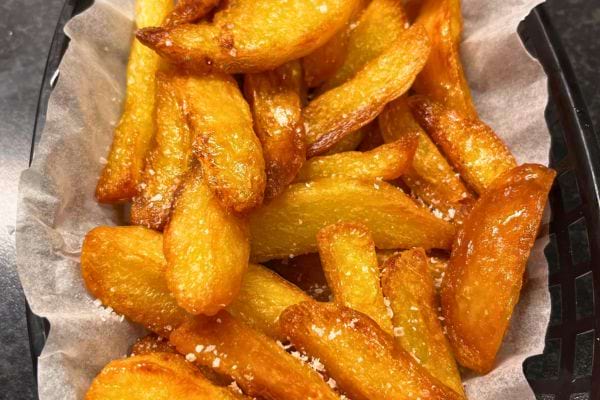 Frites épaisses, dorées, empilées sur une assiette.