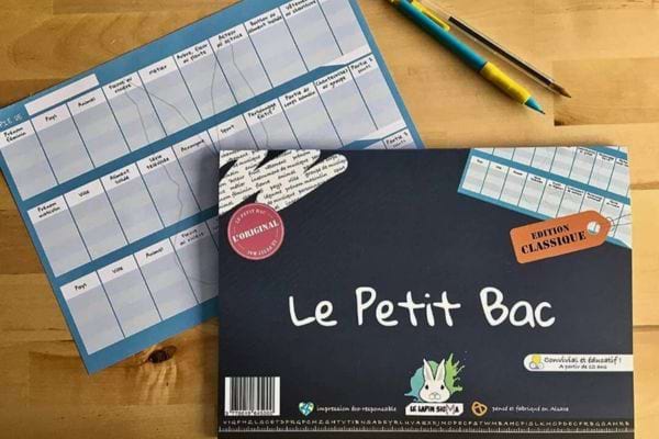 Un jeu de société "Le Petit Bac" avec des fiches et des crayons.