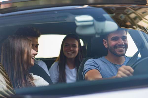 Quatre jeunes souriants en voiture.