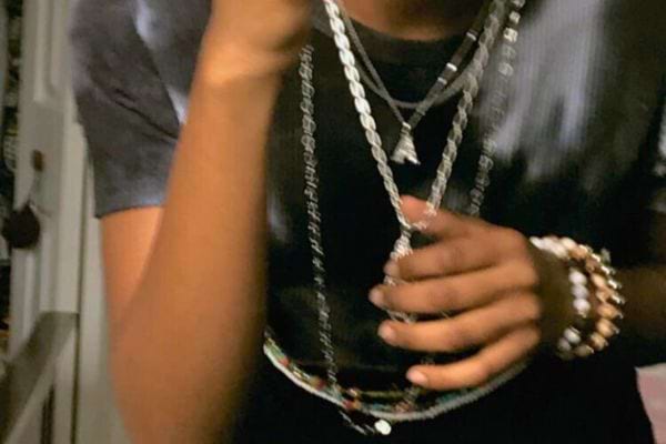 Main d'homme tenant des chaînes argentées.