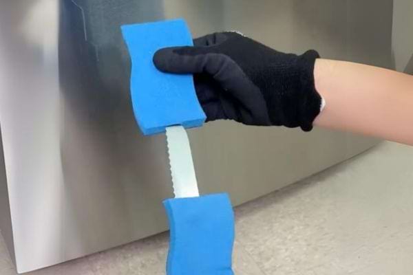 un couteau à pain et des éponges pour nettoyer sous le frigo