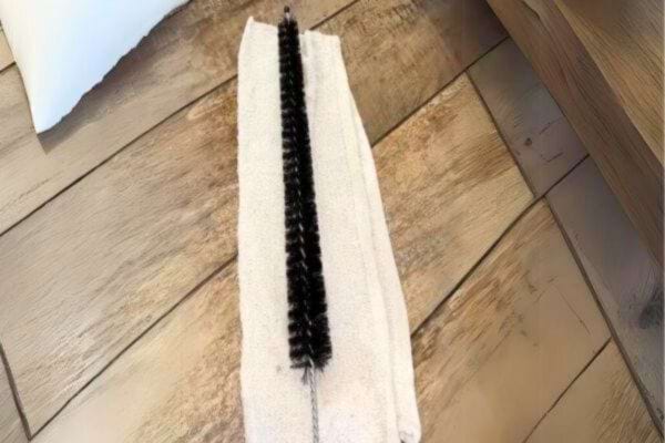 un goupillon et un chiffon pour nettoyer sous le frigo