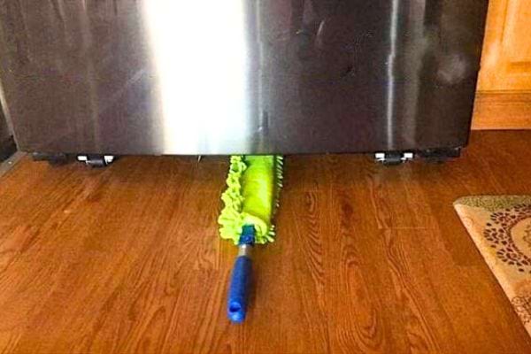 un plumeau pour nettoyer sous le réfrigérateur