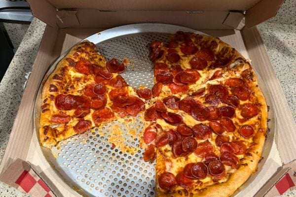 Pizza au pepperoni partiellement consommée dans une boîte.