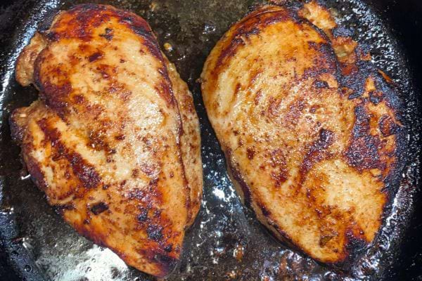 Deux poitrines de poulet grillées dans une poêle.