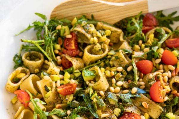 Salade de pâtes au pesto garnie de tomates et de pignons.