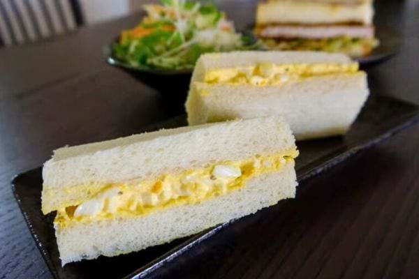 Sandwich aux œufs avec mayonnaise, servi sur une assiette noire.