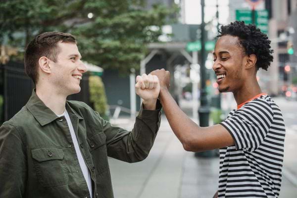Deux hommes se font un "fist bump" en ville.