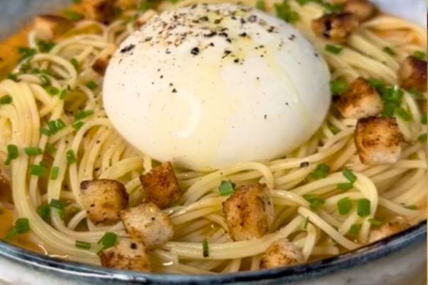 Spaghetti à la burrata, couronné d'un œuf poché et saupoudré de croutons pour un twist gourmand.