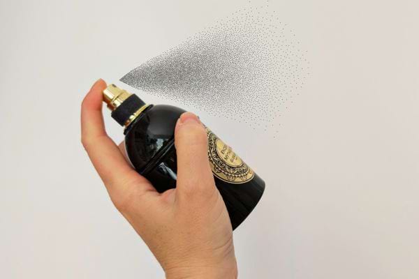Vaporisation de parfum depuis un flacon noir.
