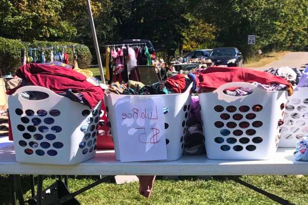 Paniers de vêtements sur une table de vente de garage.