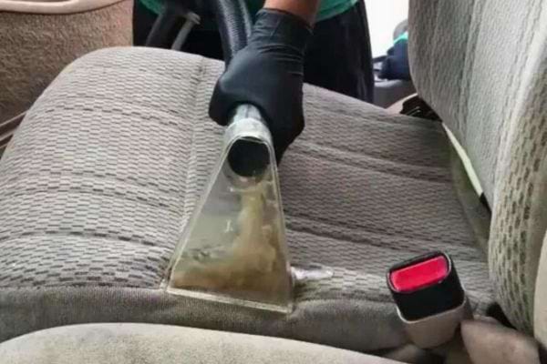 Aspirateur nettoyant un siège de voiture.