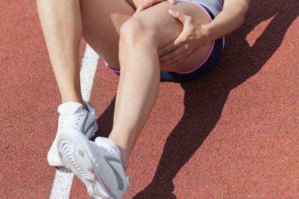 une personne avec une crampe à la cuisse sur une piste de courses à pieds