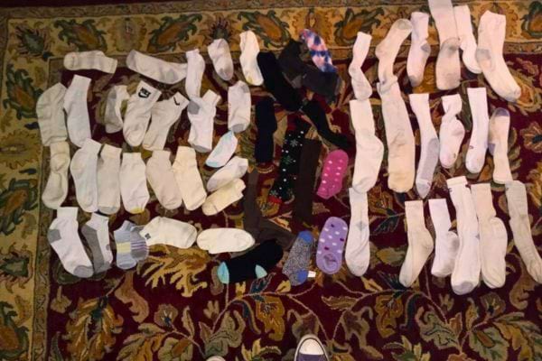 Des chaussettes dépareillées, principalement blanches, étalées sur un tapis coloré.