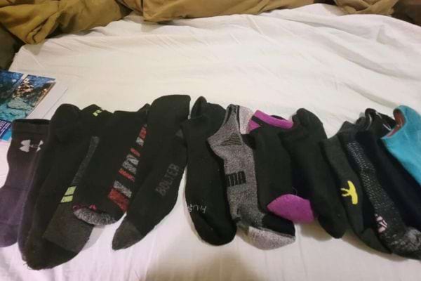 Chaussettes noires et grises dépareillées alignées sur un lit.