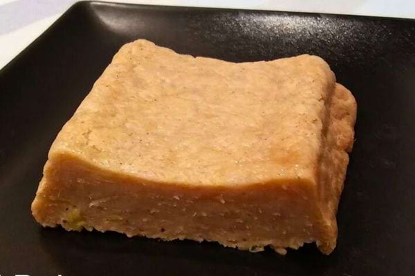 Gâteau au citron sans œufs, servi sur une assiette noire.