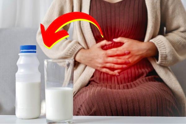 Une femme avec des douleurs abdominales, avec du lait et un verre à côté.