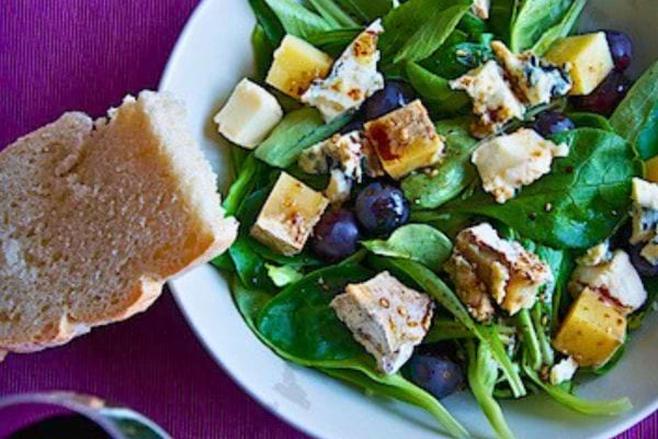 Salade verte avec cubes de fromage et raisins.
